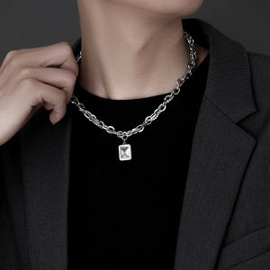 Men's silver chain necklace with rectangular clear gemstone pendant on charcoal suit