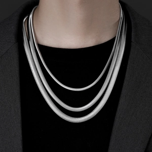Close-up of triple layered silver snake bone chains on model with dark blazer