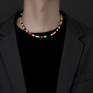 Detail of colorful beaded choker on male model wearing a grey blazer and black tee