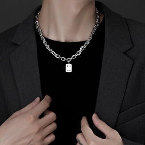 Silver cuban chain with square crystal pendant on a male model with dark background