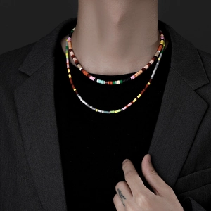 Detail of colorful double-layered beaded necklace with cylindrical charms on a male model