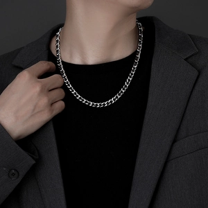 Close-up of polished silver Cuban link chain necklace worn on a male model in a suit