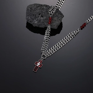Macro shot of titanium steel gothic cross necklace with red stones and fishbone chain links