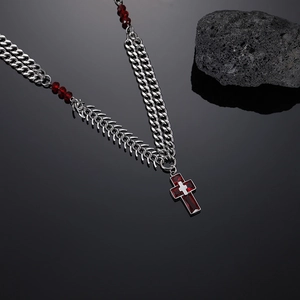 Detail of red cross pendant necklace with spinal fishbone chain and red gemstone accents