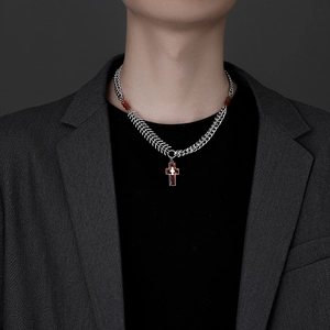 Close-up of a men's titanium steel necklace with a red cross pendant on a gray blazer suit