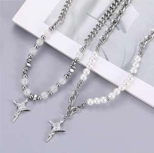 Titanium steel necklaces with irregular beads and zircon cross pendants on a minimal background