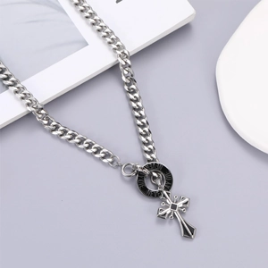 Macro view of silver Cuban chain necklace with cross pendant and black enamel ring detail