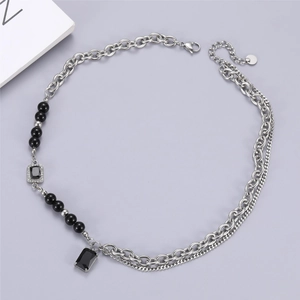 Detail of multi-layered titanium steel necklace with black gemstone and pearl accents