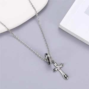 Gros plan du pendentif croix en argent et de l'anneau STARS serti sur une chaîne polie