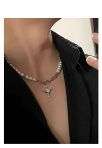 Detail of cross star necklace with pearls and silver chain worn by a model