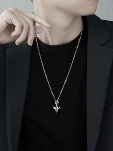 Detailed view of a silver airplane pendant necklace on a model with a black suit