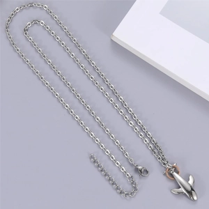 Macro detail of silver airplane pendant with rose gold ring accent on O-shaped chain