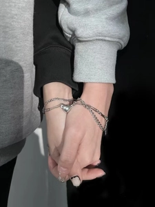 Detailed close-up of couples magnetic heart bracelets with silver Cuban and paperclip chains