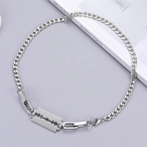 Detail of silver blade pendant with 'as sharp as ever' engraving on a cuban link chain
