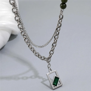 Detail of double-layer silver chain with emerald green gemstone pendant and beaded accents