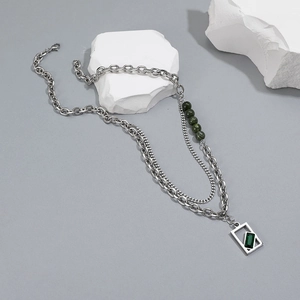 Detail of double-layered silver necklace with green beads and emerald rectangular pendant