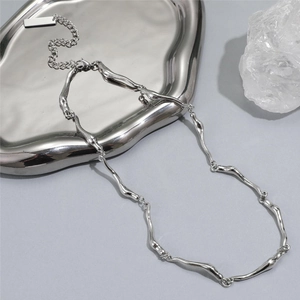Collier argenté organique irrégulier avec texture fluide sur fond de pierre