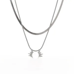 Detail of layered titanium steel necklace featuring a sunburst pendant and snake chain