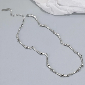 Détail d'un collier argenté à effet métal liquide avec fermoir mousqueton et étiquette