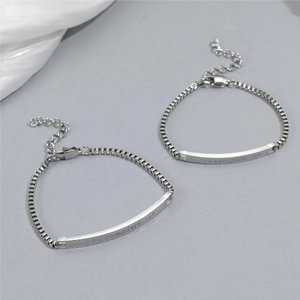 Detail of silver couple bracelet with box chain and 'you complete me' engraved bar