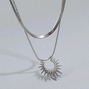 Macro detail of silver double-layered snake chain necklace with sunburst pendant