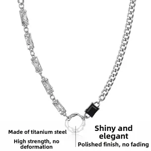 Détail d'un collier en acier titane avec maille gourmette, pierre noire et anneau poli