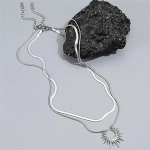 Close-up of double layer silver snake chain necklace with sun pendant on dark rock
