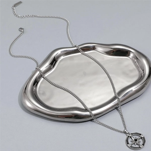 Close-up of silver compass star pendant with black bead on metallic tray