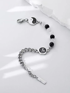 Dettaglio macro del ciondolo Tai Chi e del simbolo Dao su un bracciale in perle e metallo