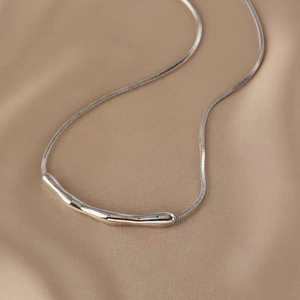 Detailed close-up of a silver irregular crinkled pendant with a sleek snake bone chain
