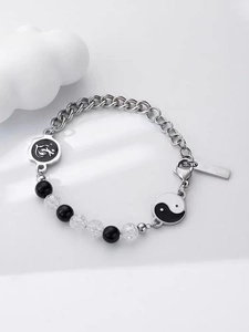 Dettaglio del ciondolo Tai Chi Yin Yang e del charm drago su un bracciale in acciaio titanio