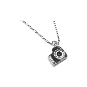 Vue détaillée du pendentif appareil photo rétro argenté avec lentille et chaîne