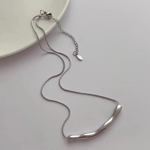 Macro shot of silver titanium steel necklace featuring an irregular wavy liquid metal pendant