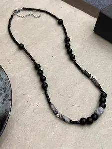 Macro shot of handmade beaded necklace with black stones and gray marble-textured beads