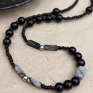 Macro detail of Chinese style beaded necklace with black beads and grey stone accents
