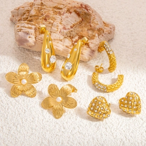 Macro view of gold heart earrings and flower studs with pearls and sparkling crystals
