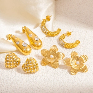 Detailed macro view of four pairs of golden heart, flower, and pearl stud earrings set