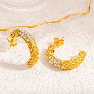 Detailed macro view of gold plated C-shaped hoop earrings with sparkling zircon inlay