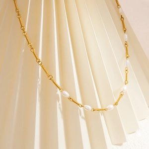 Detail of 18K gold-plated necklace featuring textured metal rods and freshwater pearls