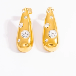 Close-up of golden teardrop earrings with embedded white zircons on a white background