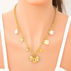 Collier en or 18K avec breloques de fleurs en perles et papillon porté par un modèle