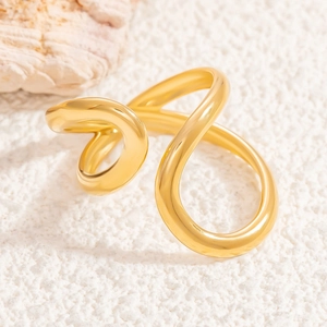 Détail macro d'une bague dorée aux formes fluides modernes sur surface texturée