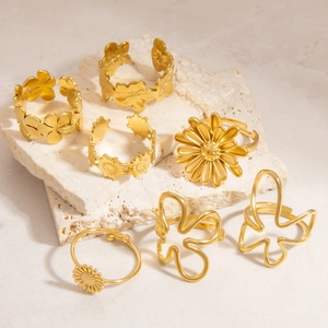 Detailed macro shot of gold flower and butterfly rings on travertine stone stand