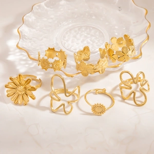 Detailed macro view of seven gold sunflower and butterfly rings on a marble surface