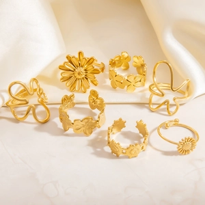 Set of seven gold floral rings with daisies and butterflies on white silk background