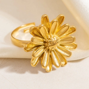Macro view of gold daisy flower ring with layered petals on white silk background