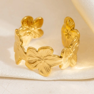 Macro shot of gold floral open ring with detailed petal textures on marble and silk