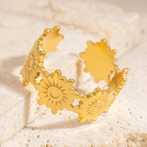 Detailed close-up of golden stainless steel daisy flower ring on natural stone