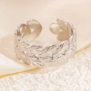 Detailed macro shot of silver leaf patterned adjustable stainless steel ring on silk