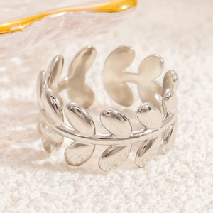 Detail shot of silver leaf-shaped open ring on soft fabric with mirror polish finish